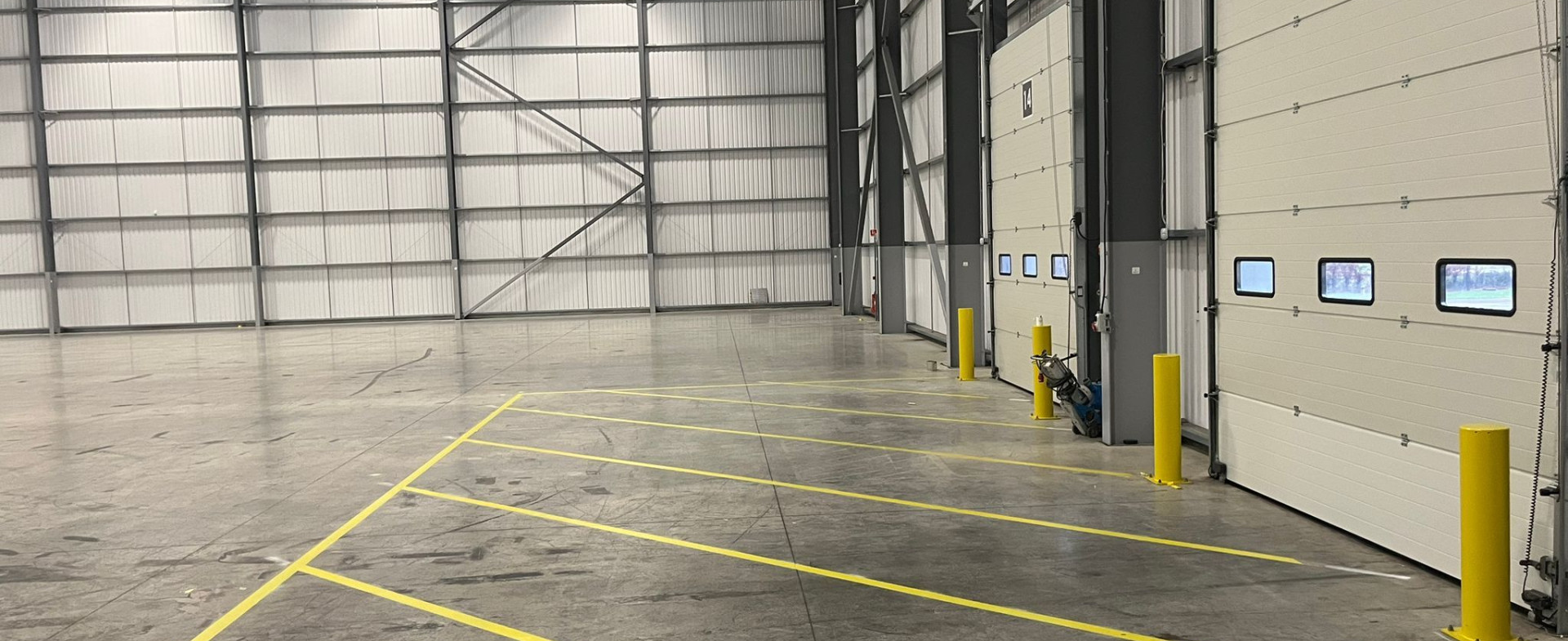 Internal warehouse safety markings showing green fire escape routes, yellow caution zones, and vehicle guidance lines at a parcel distribution hub.